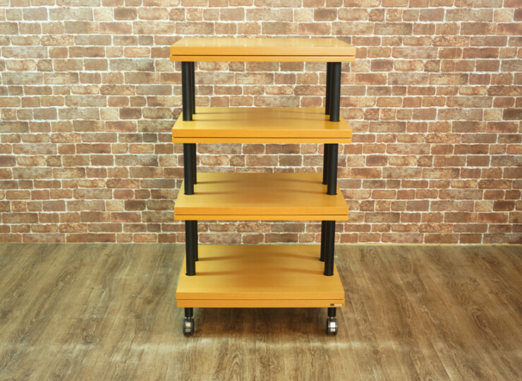 Five-tier wooden rolling cart with black vertical supports and wheels, placed on a wood floor against a brick wall.