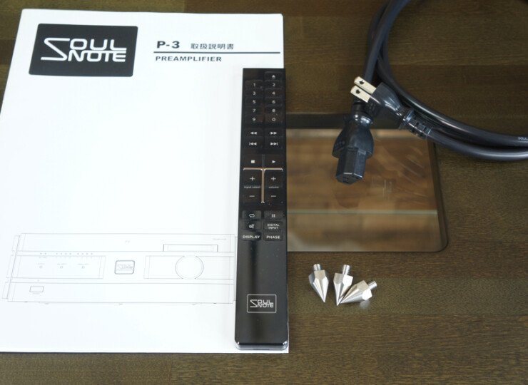 【美品】SOULNOTE P-3 2026年製 ソウルノート プリアンプ プレミアム・シルバー ワンオーナー#R09895 SoulNote P-3 preamplifier manual with a black remote control, a coiled power cord, and three metal spike feet on a wooden table.