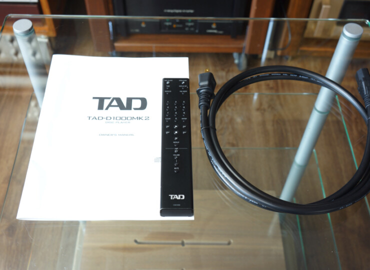TAD TAD-D1000MK2 SILVER SACD/CDプレーヤー / 384kHz・32bit対応 / リモコンあり#R09883 TAD D-1000MK2 owner's manual with a black TAD remote and a coiled cable on a glass table