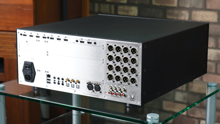 Back panel of a rack-mmounted audio device showing numerous circular DIN connectors and a power inlet on the left